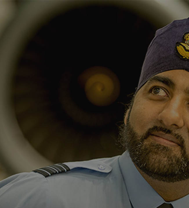 RAF Engineering Officer wearing turban stood in front of RAF Voyager engine in hanger
