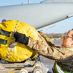 RAF mover placing bag onto aircraft cargo roller platform