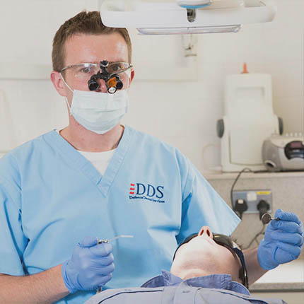 RAF Dental Officer (Dentist) in mask with magnifying glasses treating patient